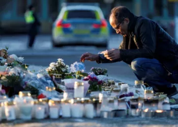 A man looks at tributes left to the victims of the shooting outside Campus Risbergska in Örebro. Photograph Kuba StężyckiReuters
