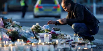 A man looks at tributes left to the victims of the shooting outside Campus Risbergska in Örebro. Photograph Kuba StężyckiReuters